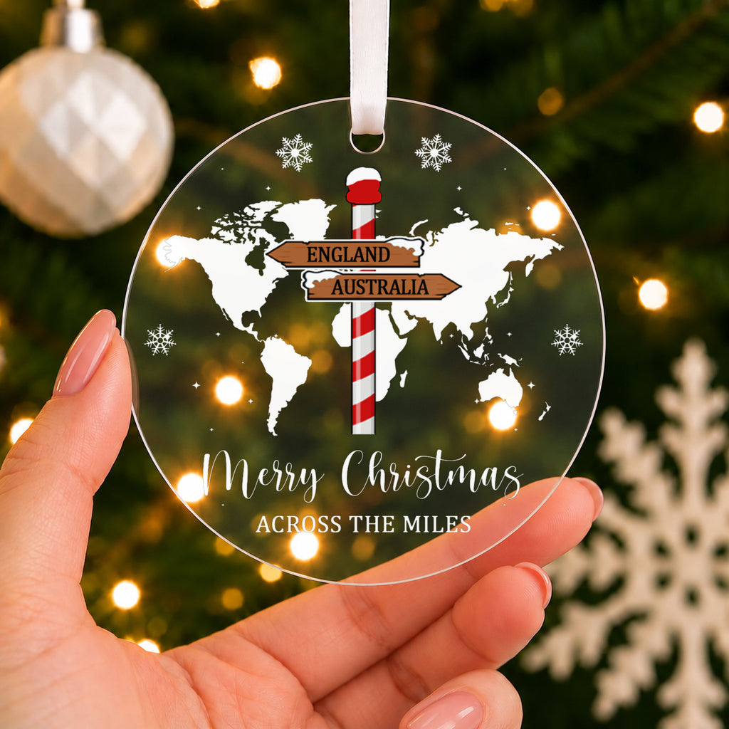 Personalised Across the Miles Christmas Bauble – World Map & Signpost – shown held in the hand